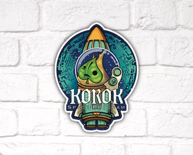 Puede incluir: Un personaje de dibujos animados verde que lleva un traje espacial y un casco, dentro de un cohete. El cohete est&aacute; rodeado por un c&iacute;rculo azul y verde con un patr&oacute;n de estrellas y remolinos. El texto "KOKOK SPACE PROGRAM" est&aacute; debajo del cohete.