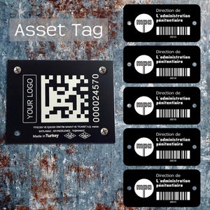 Op de afbeelding: Zwarte asset tags met witte tekst en een QR-code. De tags bevatten de tekst "YOUR LOGO" en "000024570". Extra tags tonen "Direction de L'administration pénitentiaire" en een barcode. De achtergrond is een getextureerd, metalen oppervlak.