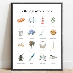 Peut inclure: Une affiche encadrée avec des illustrations à l'aquarelle d'icônes de Cape Cod, dont un rouleau de homard, un phare et un vélo. Le texte "- the joys of cape cod -" est en haut. L'affiche est sur un mur blanc au-dessus d'un sol en bois.