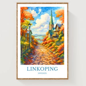 May include: Watercolor print of Linkoping, Sweden, featuring a cobblestone path leading to a church with a tall steeple. The scene is framed by vibrant autumn foliage in shades of orange and red, with a blue sky and white clouds. The print is in a wooden frame.