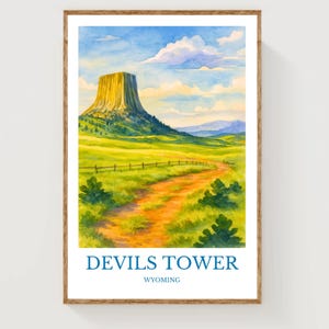 Może przedstawiać: Akwarelowy wydruk Devils Tower w Wyoming. Grafika przedstawia malowniczy krajobraz z charakterystyczną formacją skalną, polną ścieżką i żywym zielonym polem pod błękitnym niebem z chmurami. Tekst "DEVILS TOWER WYOMING" znajduje się na dole.