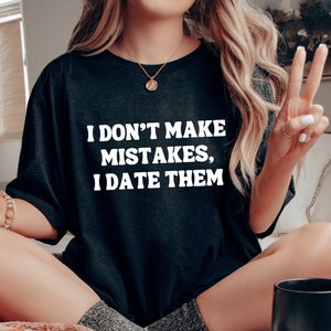 May include: A black t-shirt with white text that reads "I don't make mistakes, I date them".