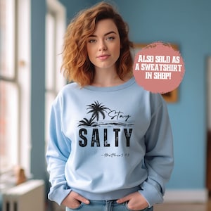 K&ouml;nnte beinhalten: Hellblauer Pullover mit einem schwarzen Aufdruck von Palmen und dem Text "Stay Salty - Matthew 5:13".