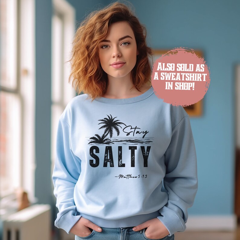 K&ouml;nnte beinhalten: Hellblauer Pullover mit einem schwarzen Aufdruck von Palmen und dem Text "Stay Salty - Matthew 5:13".