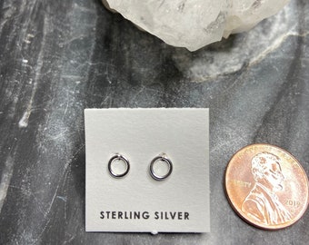 Può includere: Un paio di piccoli orecchini a cerchio d'argento su una carta bianca con il testo "STERLING SILVER".