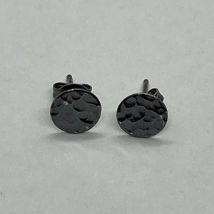 May include: A pair of black stud earrings with a hammered texture.