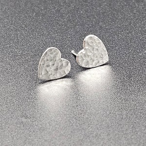 May include: A pair of silver heart-shaped earrings with a hammered texture.