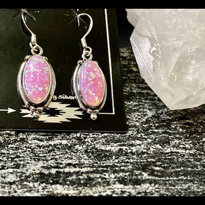 K&ouml;nnte beinhalten: Ein Paar silberne Ohrh&auml;nger mit rosafarbenen Opal-Steinen. Die Ohrringe haben ein schlichtes Design mit einem kleinen ovalen Stein.