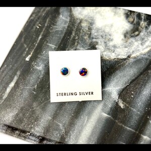 May include: A pair of sterling silver stud earrings with round, blue and red opal stones.