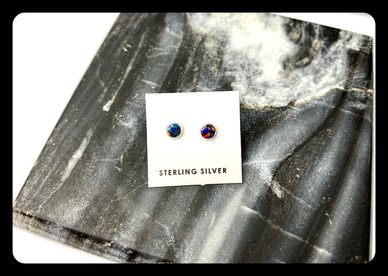 May include: A pair of sterling silver stud earrings with round, blue and red opal stones.