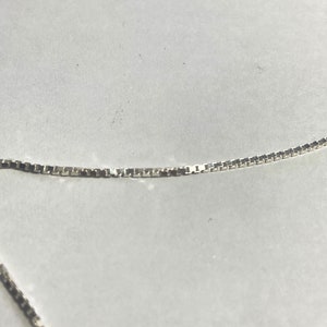 May include: A silver chain necklace with a box chain style.