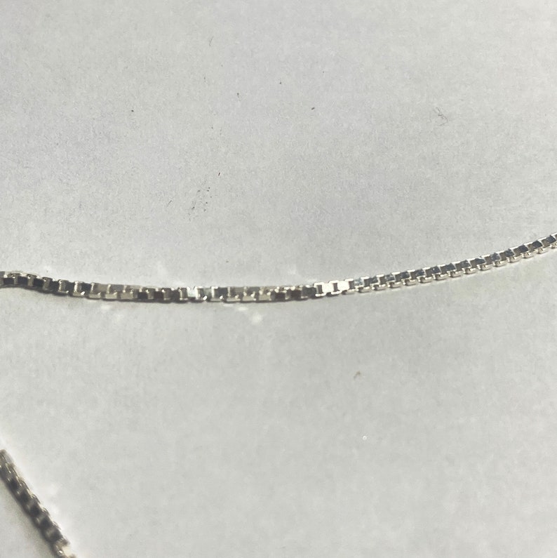 May include: A silver chain necklace with a box chain style.