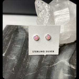Könnte beinhalten: Ein Paar Ohrstecker aus Sterlingsilber mit rosafarbenen Opal-Steinen. Die Ohrringe werden auf einer weißen Karte mit dem Text "Sterling Silver" präsentiert.