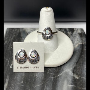 May include: Sterling silver bear paw ring and earrings with opal stones. The ring is on a white display stand and the earrings are on a card that says "Sterling Silver".
