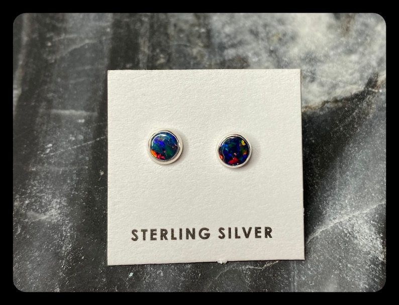 May include: A pair of sterling silver stud earrings with round black opal stones.