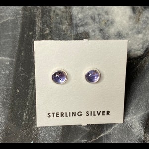May include: A pair of sterling silver stud earrings with small, round, purple gemstones.