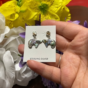 May include: Sterling silver earrings with a bear design made from abalone shell. The earrings are a light iridescent color with a mix of green, blue, and purple.