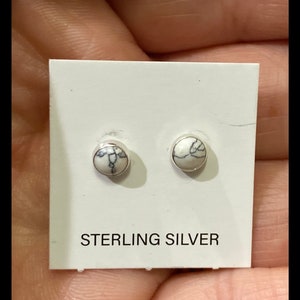 May include: A pair of sterling silver stud earrings with white howlite stones. The earrings are displayed on a white card with the text "STERLING SILVER".