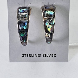 May include: A pair of sterling silver hoop earrings with abalone shell inlay. The earrings are a light brown color with iridescent blue, green, and purple hues.