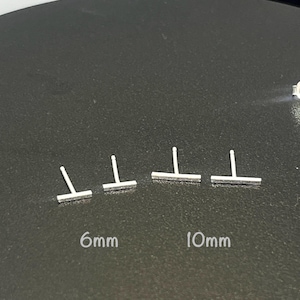 May include: Four silver bar earrings in different sizes. The earrings are arranged in a row from smallest to largest. The smallest earring is 6mm long and the largest earring is 10mm long.