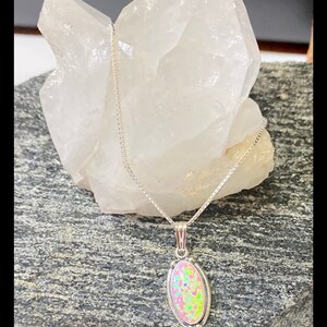 K&ouml;nnte beinhalten: Eine silberne Kettenkette mit einem ovalen Anh&auml;nger mit einem rosa und gr&uuml;nen Opal-Edelstein.