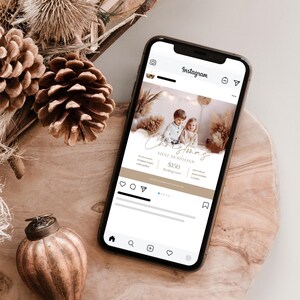 Può includere: Uno smartphone che mostra un post di Instagram che pubblicizza una mini sessione fotografica di Natale per 150 €. Il post presenta una foto di due bambini davanti a uno sfondo di fiori secchi e un albero di Natale bianco.