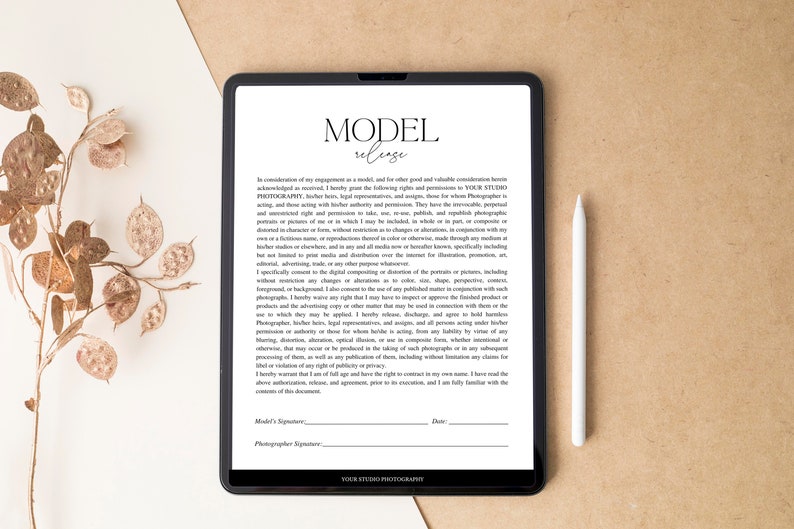 May include: A black tablet displaying a "Model Release" document, with a white stylus resting beside it. The document has text and signature lines. A decorative branch with dried seed pods is in the background.