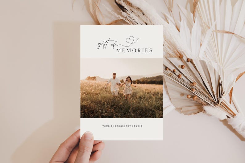 May include: A white card with the text "gift of memories" and a small heart symbol. The card has a photo of a couple holding hands and running through a field of tall grass.