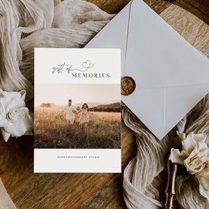 May include: A white card with the text "gift of MEMORIES" and a small heart symbol. The card features a photograph of a couple walking through a field.