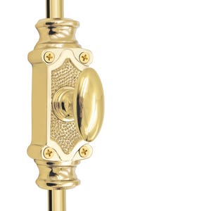 Peut inclure: Un loquet de porte en laiton poli avec une poignée ovale et des détails décoratifs. Le loquet est monté sur une tige verticale en laiton, avec un centre texturé et quatre petites vis.