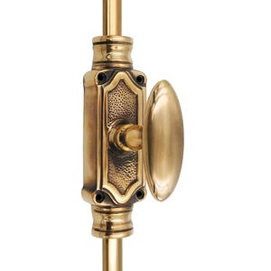 May include: A close-up of a brass door latch with an oval handle. The latch has an ornate, textured design and is mounted on a vertical rod. The hardware is a warm, golden color against a white background.