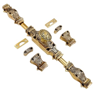 Può includere: Set di serratura per porta in ottone ornato con motivi floreali e a foglie decorativi. Il set include un lungo chiavistello, un pomello rotondo e diversi pezzi più piccoli, il tutto in una calda tonalità dorata. Il design è dettagliato e di ispirazione vintage.