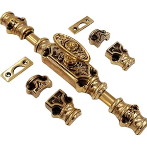 Puede incluir: Cerrojo de puerta de latón ornamentado con detalles florales decorativos. Incluye el cerrojo principal, las placas de cierre y los herrajes de montaje. La ferretería es de color dorado cálido y está diseñada para una puerta o armario.