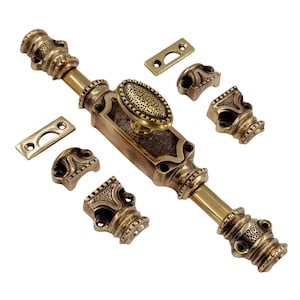 Puede incluir: Un juego de cerrojo de puerta de latón antiguo con una pieza central ovalada y detalles decorativos. El juego incluye el cerrojo principal, dos placas de cierre y cuatro piezas de montaje decorativas. El herraje es de color dorado cálido.