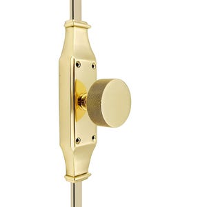 Könnte beinhalten: Ein goldfarbener Türriegel mit einem runden, gerändelten Knauf. Der Riegel ist an einer vertikalen Stange montiert.