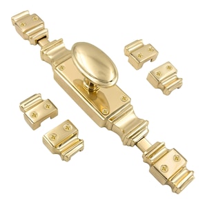 Puede incluir: Un cerrojo de armario de latón pulido con un asa ovalada y placas de cierre a juego. El cerrojo es rectangular con bordes decorativos y se asegura con tornillos pequeños. El herraje está diseñado para puertas o armarios.