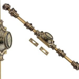 Puede incluir: Un cerrojo de puerta de latón antiguo con detalles ornamentados. El cerrojo presenta un mango ovalado y detalles decorativos. Incluye dos placas de cierre a juego. El herraje está diseñado para una estética clásica o vintage.