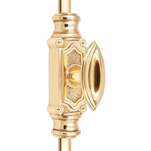 May include: A polished brass window sash lock with an ornate design. The lock features a decorative oval handle and is mounted on a vertical bar. The brass finish gives it a classic, elegant look. The lock is designed for window security.