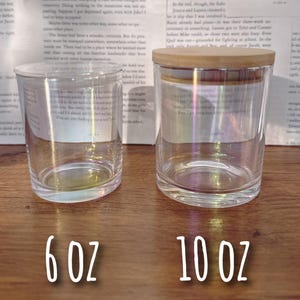 May include: Two clear glass jars with iridescent effects, one with a wooden lid. The jars are labeled with white text indicating their capacity: 6 oz and 10 oz. The jars are cylindrical and sit on a wooden surface.