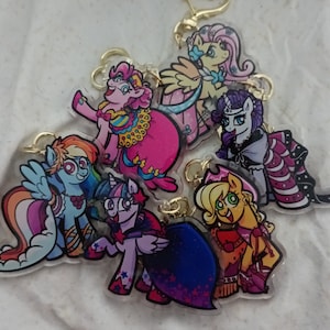 May include: A set of six colourful cartoon pony keychains. The keychains feature different pony characters with various hairstyles and accessories. The ponies are depicted in a whimsical style with bright colours and bold outlines.