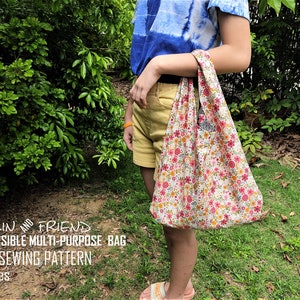 May include: A reversible multi-purpose bag with a floral pattern is held by a person. The bag is white with pink, yellow, and orange flowers. The text "MALIN AND FRIEND REVERSIBLE MULTI-PURPOSE BAG PDF SEWING PATTERN 3 Sizes" is visible.