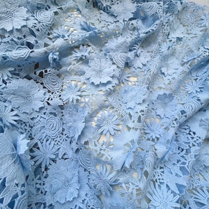 Pu&ograve; includere: Tessuto di pizzo blu chiaro con un motivo floreale. Il tessuto &egrave; realizzato in pizzo delicato e intricato con fiori in rilievo.