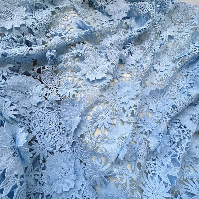 Pu&ograve; includere: Tessuto di pizzo blu chiaro con un motivo floreale. Il tessuto &egrave; realizzato in pizzo delicato e intricato con fiori in rilievo.