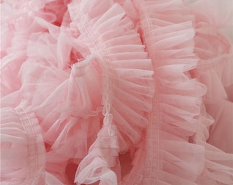 May include: Pink ruffled trim with a delicate, sheer texture. This trim is perfect for adding a touch of elegance to any project.