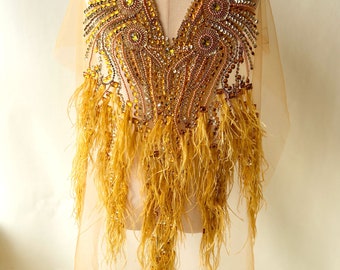 May include: A gold and yellow beaded applique with feather fringe. The applique is designed in a V-shape and is perfect for adding a touch of sparkle to any garment.