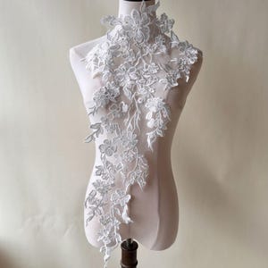 May include: White floral lace applique with delicate flowers and leaves. This lace trim is perfect for adding a touch of elegance to any project.
