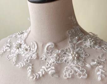 May include: White lace trim with pearl embellishments. The trim features a delicate floral design and is perfect for adding a touch of elegance to any project.