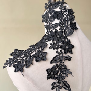 May include: Black floral lace trim with a delicate design featuring small flowers and leaves. This trim is perfect for adding a touch of elegance to any project.