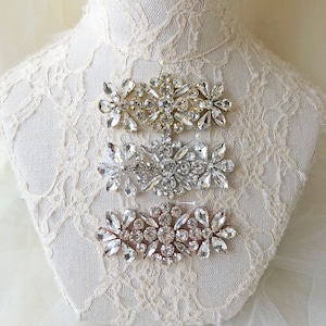 Può includere: Tre decorazioni in strass dorati, argentati e oro rosa. Ogni decorazione presenta un motivo floreale con strass trasparenti.