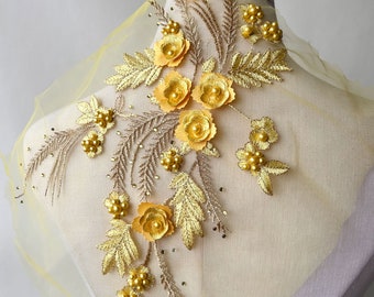 May include: A yellow floral applique with pearl accents and gold embroidery. The applique is on a yellow mesh fabric.